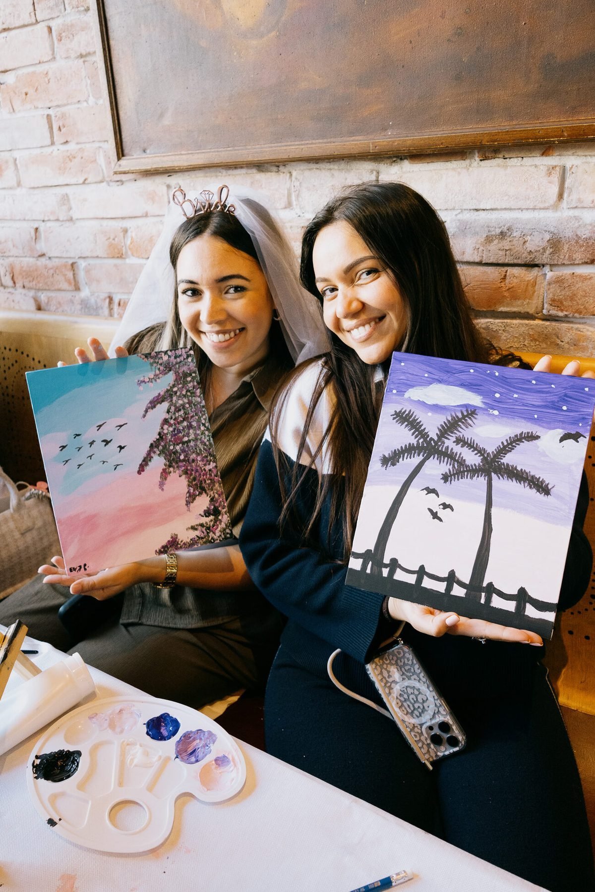 Deux participantes souriantes présentant les toiles qu’elles viennent de terminer