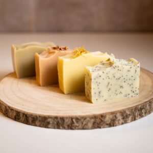 Quatre savons naturels faits main posés sur une rondelle de bois, atelier With Nürya à Genève